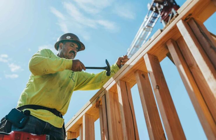 werkman in high-visibility kleding die timmert op hout